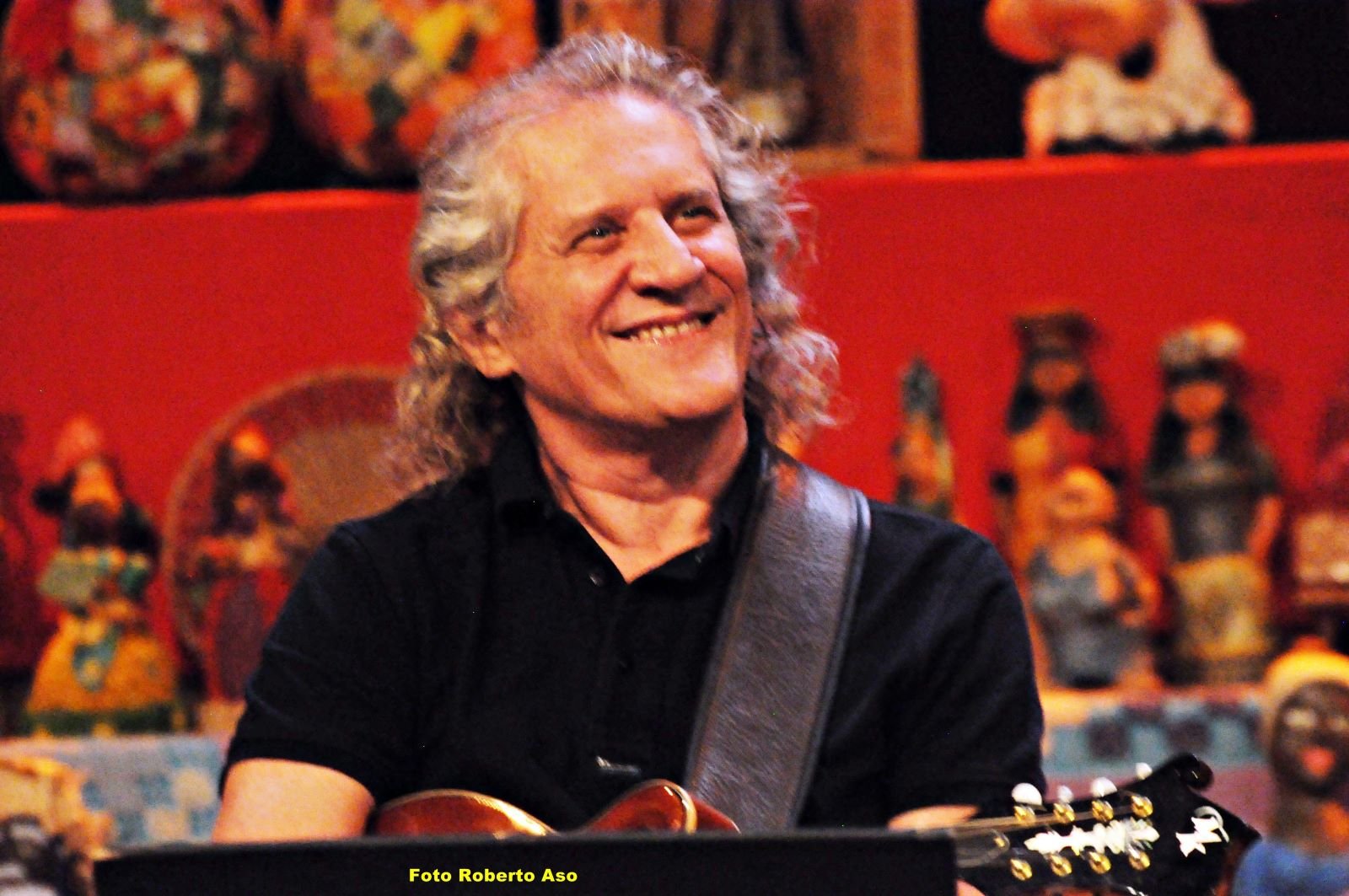 projeto-concerto-bandolim-ney-marques Ney Marques sorrindo, de camisa preta com bandolim pendurado. Músico, compositor, arranjador, produtor musical e diretor artístico, no programa do Boldrin.